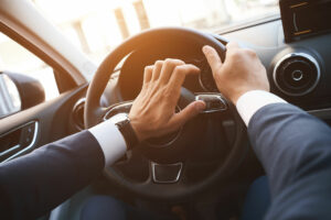 man driving a car with a hand on a horn