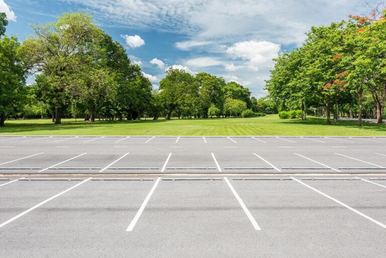 mpty parking lot against green lawn in city park
