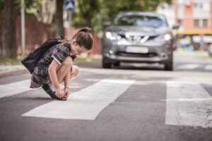 Girl fixing her shoes on at the crosswalk